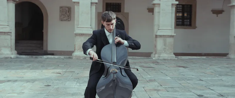 Vito am Cello vor hellen Arkaden
