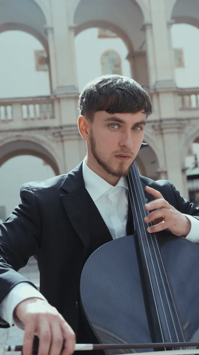Vito mit Cello vor den Arkaden eines historischen Innenhofs